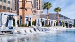 Pool with white lounge chairs and cabanas behind them